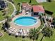 Aerial view of a community pool with lounge chairs, tables, red tile roof, and well-maintained landscaping at 758 Village Cir # 106, Venice, FL 34292