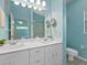 Light-blue bathroom with white cabinets, double sinks, and large mirror offering a glimpse of the bedroom at 904 Addington Ct # 204, Venice, FL 34293