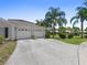 Exterior view of a home showcasing a two-car garage, driveway, well-kept lawn, and lush trees at 904 Addington Ct # 204, Venice, FL 34293
