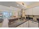 Kitchen with granite counters, stainless steel sink, and white cabinetry, offering views into the living area and ocean at 950 Tarpon Center Dr # 504, Venice, FL 34285