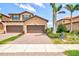 Townhome features a two-car garage with a brick paver driveway and lush landscaping at 10808 Tarflower Dr # 102, Venice, FL 34293