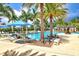 A relaxing pool area with palm trees, sun loungers, and bright blue umbrellas for a resort-style living experience at 10808 Tarflower Dr # 102, Venice, FL 34293