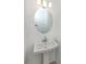 Compact bathroom featuring a pedestal sink, oval mirror, and modern lighting, creating a clean aesthetic at 11228 Fieldstone Dr, Palmetto, FL 34221