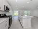 Well-lit kitchen featuring stainless steel appliances, modern cabinets, an island with sink, and sliding glass door at 11228 Fieldstone Dr, Palmetto, FL 34221
