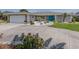 View of the home's exterior features well-maintained landscaping, a turquoise door, and a spacious driveway leading to the garage at 1234 Paradise Way, Venice, FL 34285