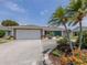 View of the home's exterior showcases beautiful landscaping, a bright turquoise door, and a spacious driveway and garage at 1234 Paradise Way, Venice, FL 34285