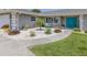 View of the landscaped circular front yard featuring modern xeriscaping and bright turquoise chairs in front of the home at 1234 Paradise Way, Venice, FL 34285