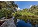 Waterfront view with a wooden dock under the canopy of lush trees and foliage at 1234 Paradise Way, Venice, FL 34285