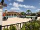 A community pool featuring lounge chairs and tables, set against a backdrop of lush landscaping and a clubhouse at 12728 Richezza Dr, Venice, FL 34293