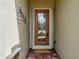 Close-up of the front door featuring decorative glass and a welcome mat on paver tiles at 12728 Richezza Dr, Venice, FL 34293
