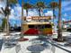 Outdoor dining area at Pop Dawgs, featuring colorful building, tables, and palm trees at 12728 Richezza Dr, Venice, FL 34293