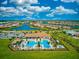 Aerial view showcasing a community pool with clubhouse and surrounding residential area by a lake at 13873 Karina St, Venice, FL 34293