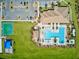 Aerial view showcasing a community pool, basketball court, playground, and clubhouse surrounded by lush green spaces at 13873 Karina St, Venice, FL 34293