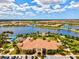 Aerial image featuring a community clubhouse, pool, lake, and residential housing at 13873 Karina St, Venice, FL 34293