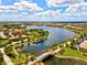 An aerial view of a picturesque community with homes surrounding a large lake with a bridge walkway at 13873 Karina St, Venice, FL 34293