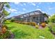 Landscaped backyard featuring a screened-in lanai with outdoor seating and manicured garden beds with colorful flowers at 13873 Karina St, Venice, FL 34293