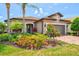 Inviting single-story home showcasing a lush garden, a brick driveway, and an attached two-car garage at 13873 Karina St, Venice, FL 34293
