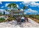Outdoor firepit with chairs under a shaded pavilion, surrounded by palm trees and landscaping at 13873 Karina St, Venice, FL 34293