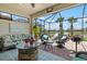 Screened lanai with wicker seating, a stone fire pit, and a tranquil view of the lake and palm trees at 13873 Karina St, Venice, FL 34293