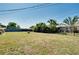 Spacious backyard with lush lawn, palm trees, and a secure black iron fence at 140 Poinsettia Ne Cir, Port Charlotte, FL 33952