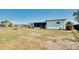 Expansive grassy backyard with a view of the rear of the white house and partial views of the lanai at 140 Poinsettia Ne Cir, Port Charlotte, FL 33952