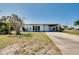 Front exterior of the white home with driveway, carport, landscaping, and blue door at 140 Poinsettia Ne Cir, Port Charlotte, FL 33952