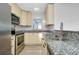 Well-lit kitchen with stainless steel appliances, granite countertops, and cream-colored cabinets at 140 Poinsettia Ne Cir, Port Charlotte, FL 33952