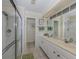 Bathroom with double vanity, white cabinets, a large mirror, and a glass-enclosed shower at 143 Braemar Ave, Venice, FL 34293
