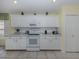 Well-lit kitchen with white appliances, white cabinetry, and tile flooring at 143 Braemar Ave, Venice, FL 34293