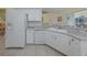 Bright kitchen featuring white cabinets, appliances, and a breakfast bar with views to dining at 143 Braemar Ave, Venice, FL 34293