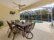 Screened in patio has a ceiling fan and a dining table with chairs with a pool in the background at 143 Braemar Ave, Venice, FL 34293