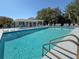 Community swimming pool and sun lounging area with a pergola and several trees near the fence line at 143 Braemar Ave, Venice, FL 34293