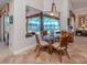 Cozy dining area with rattan chairs and a view of the screened-in pool and waterfront through a large window at 148 Wading Bird Dr, Venice, FL 34292
