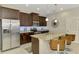 Kitchen island with stainless steel appliances, granite countertops, brown cabinets, and tile floors at 20636 Swallowtail Ct, Venice, FL 34293