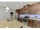 Kitchen with stainless steel appliances, granite countertops, brown cabinets, and view of laundry room at 20636 Swallowtail Ct, Venice, FL 34293