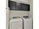 A well-equipped laundry room featuring a modern washer, dryer, and overhead cabinets at 20636 Swallowtail Ct, Venice, FL 34293