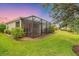 Lush backyard showcasing the screened-in lanai, lush lawn, and mature landscaping for ultimate privacy at 2150 Snapdragon Ln, Venice, FL 34292