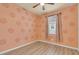 Cozy bedroom with decorative accent wall, ceiling fan, window with curtains, and modern wood-look flooring at 2150 Snapdragon Ln, Venice, FL 34292