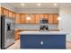 A modern kitchen featuring stainless steel appliances, white countertops, light-colored wood cabinets, and an island at 2150 Snapdragon Ln, Venice, FL 34292