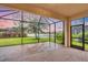 Relaxing screened-in lanai with brick flooring and views of the lake and lush backyard landscaping at 2150 Snapdragon Ln, Venice, FL 34292