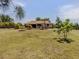 Expansive backyard with lush lawn, mature trees, and a charming single-story home featuring a covered patio at 2331 Mission Valley Blvd, Nokomis, FL 34275