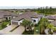 Picturesque aerial view of a modern home with lush landscaping, a tile roof, and a serene lake view at 249 Tracino Ter, Nokomis, FL 34275