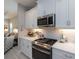 Stylish kitchen featuring white cabinets, stainless steel appliances, and a view into the cozy living room at 249 Tracino Ter, Nokomis, FL 34275