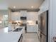 Modern kitchen boasting white cabinets, stainless steel appliances, quartz countertops, and ample natural light at 249 Tracino Ter, Nokomis, FL 34275