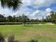 Beautiful view of community pond surrounded by lush green lawns and mature trees on a sunny day at 249 Tracino Ter, Nokomis, FL 34275