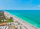 Stunning aerial view of the beach, featuring clear turquoise water and sandy shoreline with a fishing pier in the distance at 301 Gulf Dr, Venice, FL 34285