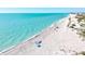 Aerial view of a sandy beach and blue water on a sunny day with a relaxing scene featuring people and umbrellas at 301 Gulf Dr, Venice, FL 34285