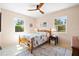 Inviting bedroom with a wood-frame bed, ceiling fan, two windows, and a decorative rug at 301 Gulf Dr, Venice, FL 34285