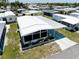 Bright home boasts carport, screened porch, white exterior and lush landscaping at 304 Roma Rd, Venice, FL 34285