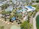 Overhead shot of the community pool, shuffleboard courts and clubhouse, set amongst palm trees and a serene pond at 304 Roma Rd, Venice, FL 34285